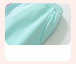 Detail of mint green girl's hoodie with elastic waistband and purple stitched pockets