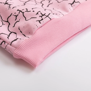 Detail of pink cotton sweatshirt with black marble print and ribbed knit cuff texture