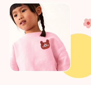 Detailed view of pink long-sleeved girls' sweatshirt with cute brown bear applique