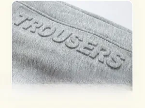 Detail of grey knitted thermal pants with 3D embossed TROUSERS lettering on fabric