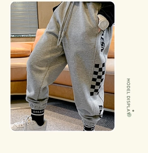 Detail of grey fleece kids pants featuring side letter print and checkerboard pattern
