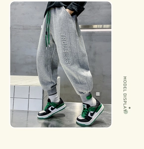 Detail of grey fleece children's trousers with TROUSERS embroidery and green drawstring