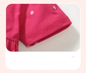 Detalle de manga de vestido rosa para niña con estampado floral blanco y costuras finas