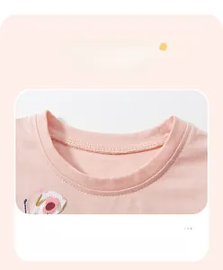 Detail of pink cotton girl's dress neckline with fine stitching and butterfly embroidery