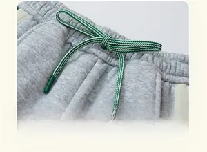 Detail of children's fleece joggers featuring elastic waist and green drawstring cord