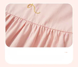 Detail of pink cotton girl's dress with smocking waist and golden embroidery design