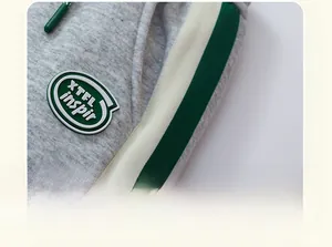 Detail of grey fleece-lined joggers with green and beige striped tape and logo patch