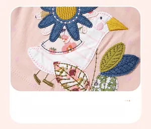 Detail of pink cotton dress showing bird and sunflower embroidery with purple dots