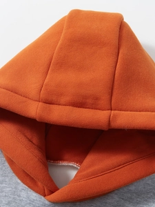 Dettaglio felpa con cappuccio per bambini con cuciture arancioni e tessuto in cotone