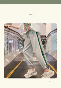 Detail of kids grey joggers with side stripes and a green circular patch on a boy