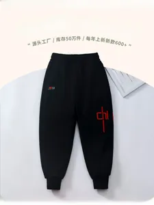 Detail of kids black fleece-lined trousers with elastic waist and red graphic print