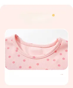 Détail d'une robe en tricot rose à col rond pour fille avec un motif à pois rouges