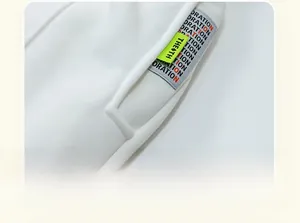 Detail of white cotton pants featuring a gray decorative strip and neon green logo tag