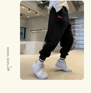 Detail of kids black fleece-lined joggers featuring China embroidered patch and cuffed ankles