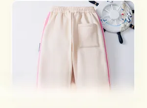 Detailed view of beige fleece-lined kids pants featuring pink side stripes and back pocket
