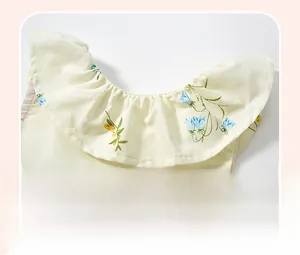 Dettaglio del collo a balze su abito estivo da bambina in cotone con motivo floreale