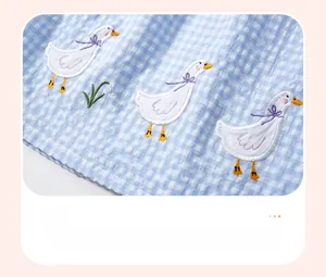 Détail du tissu en coton seersucker à carreaux bleus avec broderie appliquée de canards
