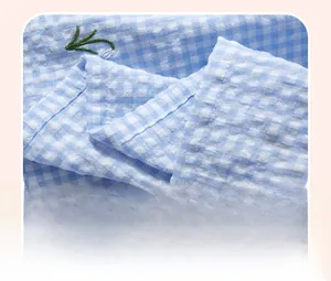 Détail de tissu à carreaux vichy bleu et blanc avec broderie florale et couture fine