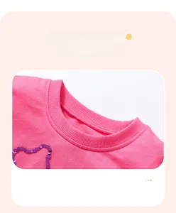 Détail de l'encolure en coton rose avec couture plate et cœur en paillettes violettes