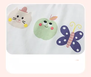 Close-up of soft white cotton fabric with cute cartoon cat and apple prints for girls
