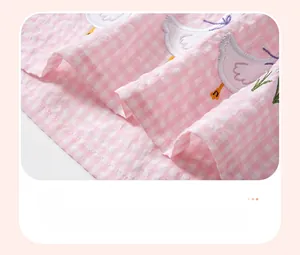 Détail de l'ourlet de robe à carreaux roses avec broderie canard et nœud violet