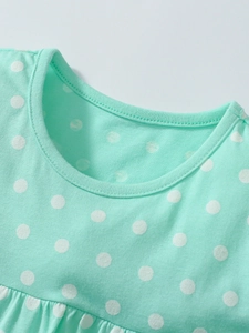 Mint green cotton dress with white polka dots featuring a round neck and pleated details