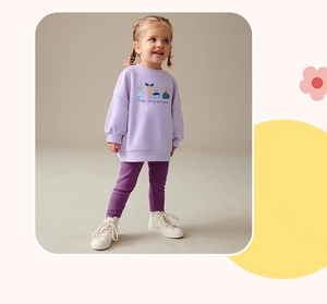 Dettaglio felpa viola da bambina con ricamo di carote e pantaloni coordinati