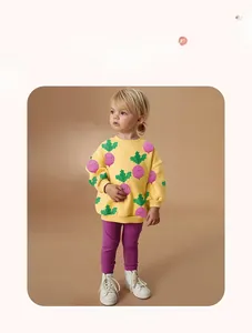 Detail view of yellow sweatshirt with purple radish pattern and matching purple pants