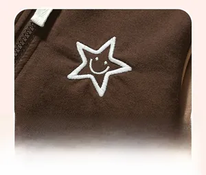 Close-up of star embroidery with smiley face on dark brown knitted kids sweatshirt