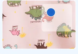 Detailed close-up of pink cotton fabric with colorful cartoon dinosaur print and patterns