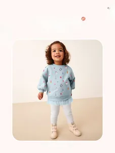 Detail view of light blue holiday kids top featuring festive prints and mesh tulle hem