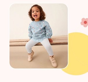 Detail of baby girl's light blue Christmas print sweatshirt and white knit leggings