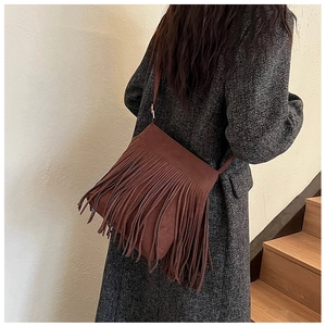 Détail du sac à bandoulière en daim marron foncé avec de longues franges sur le modèle