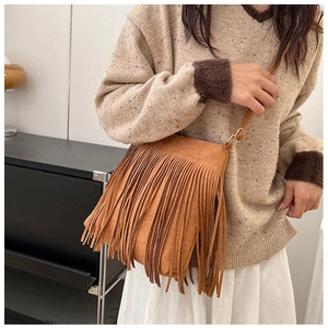 Détail d'un sac bandoulière marron en daim avec de longues franges et boucle