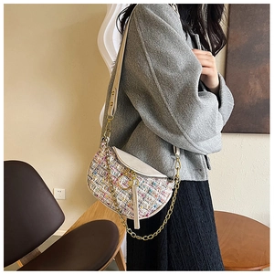 Detail of tweed crossbody bag with gold chain and white leather strap on female model