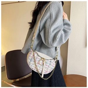 Detail of tweed crossbody dumpling bag with leather strap worn by a female model