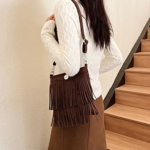 Detail of dark brown suede crossbody bag featuring dense fringe and silver buckle