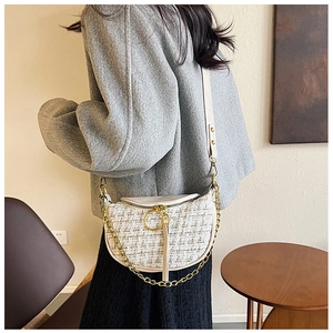 Detail of tweed crossbody crescent bag with gold chain strap on female model