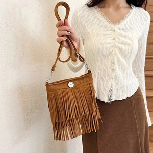 Detail of a brown suede bucket bag featuring long fringe layers and metal hardware