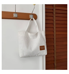 Primer plano de bolso tote de pana blanca con un parche de cuero marrón de alta calidad