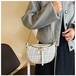 Detail of cream tweed crossbody bag with elegant texture and golden chain strap