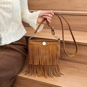 Detail of brown suede crossbody bucket bag with bohemian fringe and silver buckle