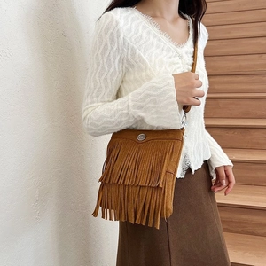 Detail view of brown suede bucket bag with long tassels and silver metal ring buckle