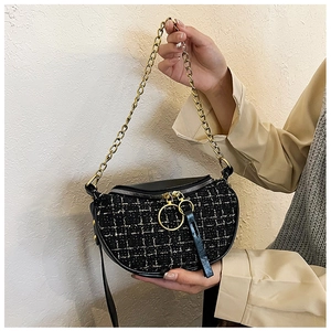 Detail of tweed crossbody bag with gold chain strap and textured woven pattern