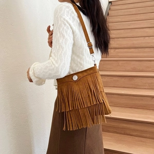 Brown suede tassel bucket bag shown on shoulder, highlighting style and large capacity