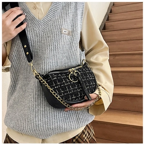 Detail view of tweed crossbody bag with golden chain and black leather strap on model