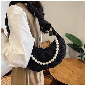 Detail of black quilted cloud bag with white pearl strap and pleated shoulder design