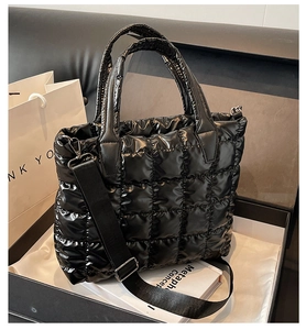 Detailed view of black quilted puffer tote bag with glossy finish and wide shoulder strap