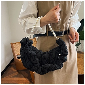 Detail of black pleated cloud bag featuring large imitation pearl handle and quilted nylon texture