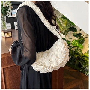 Detail of white ruched crescent bag featuring pearl chain strap and gathered wide handle